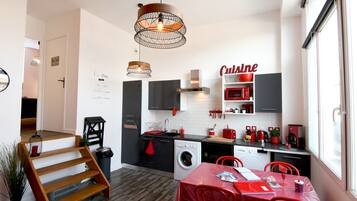 Una cocina moderna con comedor, con una decoración en rojo y negro, lavadora y un cartel rojo en la pared.