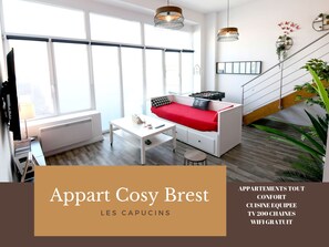 A modern apartment with a sofa, a small table, and a TV. It has large windows, a staircase, and potted plants. - Appart Cosy Brest Les Capucins (Brest)