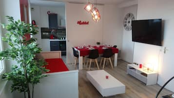 A modern apartment with a dining area, kitchenette, and a TV. It includes amenities like a TV with 200 channels and free WiFi.