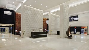 A modern hotel lobby with a reception desk, seating area, and decorative wall panels. - Hyatt Place Dubai Jumeirah Residences (Dubai)