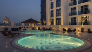 A rooftop pool area with lounge chairs, a small gazebo, and a building with multiple floors and large windows. - Hyatt Place Dubai Jumeirah Residences (Dubai)