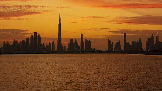 A city skyline at sunset with a prominent tower silhouetted against the sky. - Hyatt Place Dubai Jumeirah Residences (Dubai)