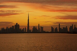 Un horizonte urbano al atardecer, con una torre destacada silueteada contra el cielo.