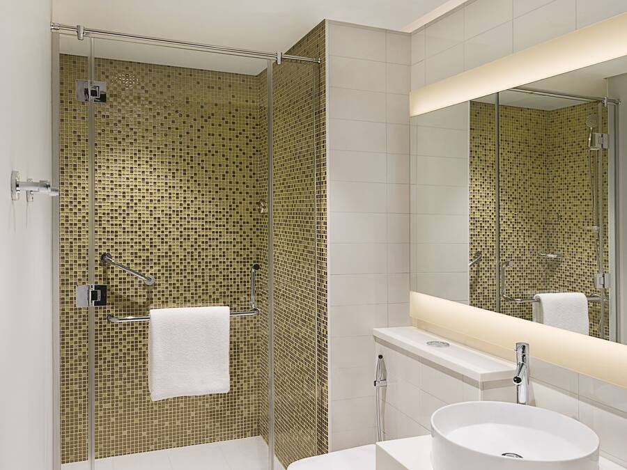 Un baño moderno con ducha envuelta en vidrio, un lavabo blanco y un espejo grande.