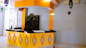 A reception area with a yellow and orange counter, a black decorative panel, and a white curtain.