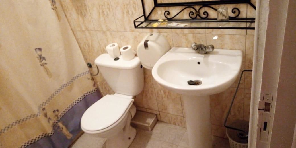 A small bathroom with a toilet, a sink, and a shower area.