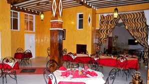 A dining area with tables set for multiple people, featuring red tablecloths and metal chairs.