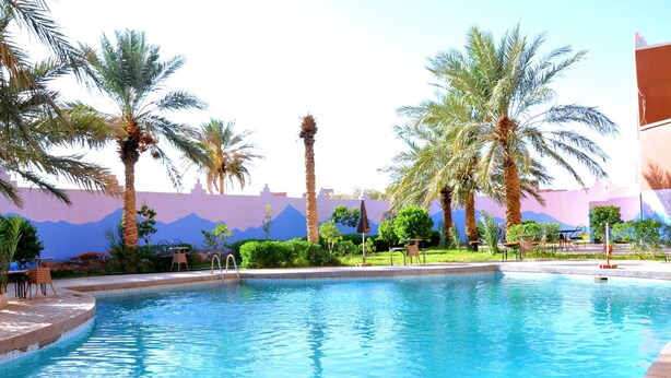 A swimming pool with palm trees and outdoor seating.