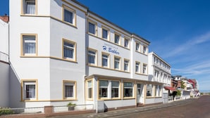 Un edificio blanco con detalles amarillos y varias ventanas, con la leyenda "Gastehaus Bakker".