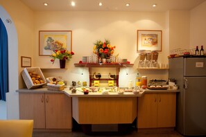 A kitchen with a central island, wooden cabinets, a refrigerator, and various food items and utensils. - Gästehaus Bakker (Norderney)