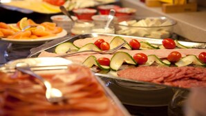 Un bufé con diversas opciones de comida, incluyendo carnes, quesos y verduras frescas.