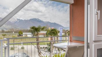 A balcony with a table and chairs, a view of mountains, and a sign for 'HAPIMAG'.