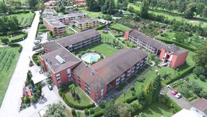 An aerial view of a residential area with multiple buildings, green spaces, and a lake in the background. - Hapimag Resort Ascona (Ascona)