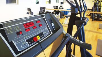 A Tunturi treadmill with digital displays and control buttons, located in a gym with exercise equipment and mirrors on the wall.