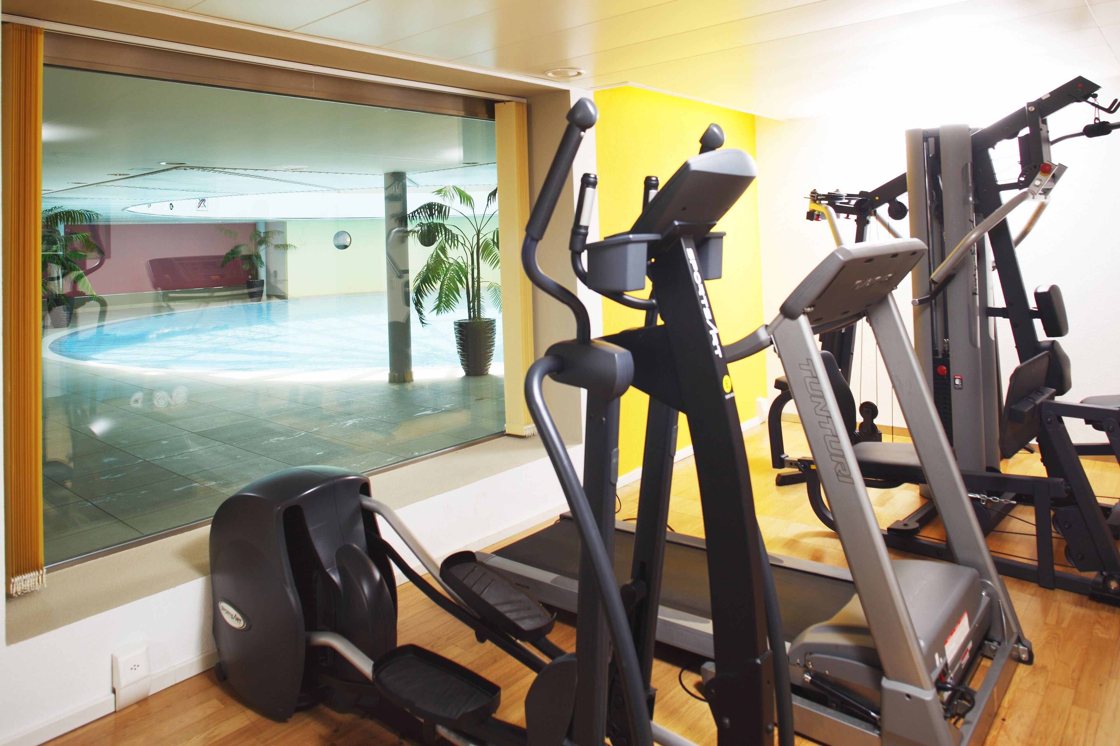 Een sportschool met loopbanden, een crosstrainer en een roeiapparaat.