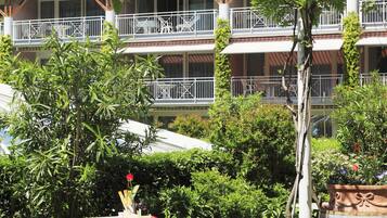 A courtyard with a table set for dining, surrounded by potted plants and a wooden barrel.