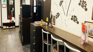 A modern kitchen area with a bar counter, bar stools, a refrigerator, and a wall-mounted decoration. - Sweet Dream Roma Termini (Rome)