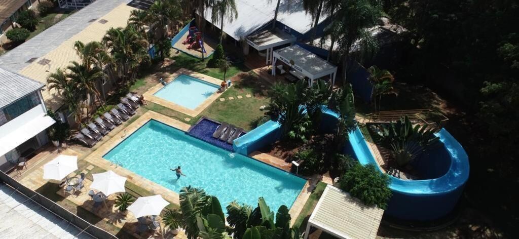 A swimming pool with a slide, lounge chairs, and palm trees.