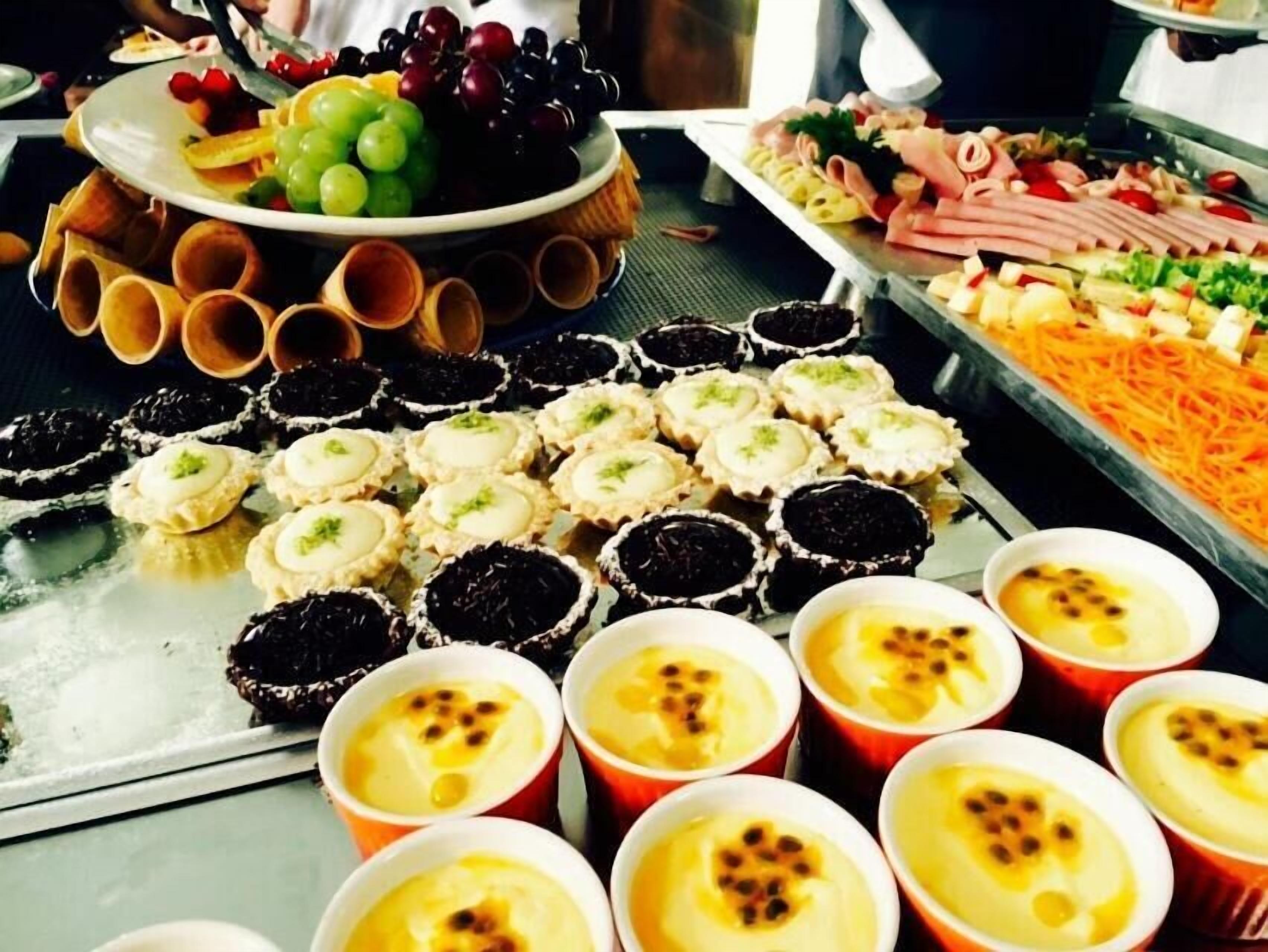 Un bufé con diversos alimentos, incluyendo cupcakes, una bandeja de frutas y una selección de carnes.