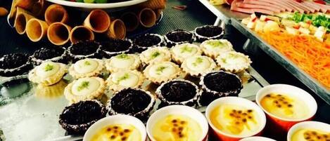 Un bufé con diversos alimentos, incluyendo cupcakes, una bandeja de frutas y una selección de carnes.