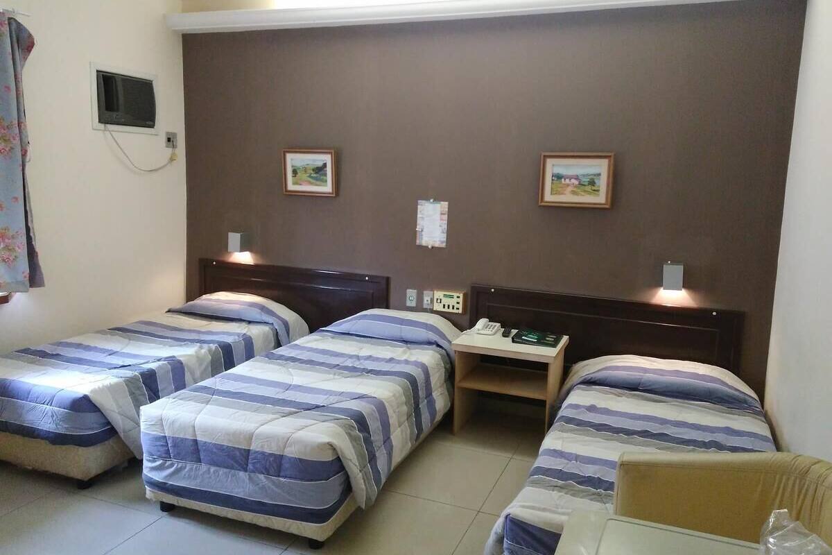 Een hotelkamer met drie eenpersoonsbedden, een bureau en een stoel.