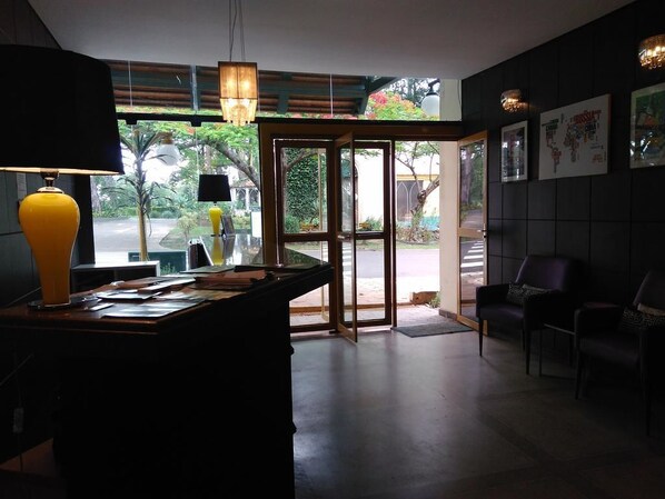 A modern interior with a desk, chairs, and a glass door leading outside. - Casa Amarela Executive Hotel (Avare)