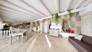 Una habitación amplia con techo alto, paredes de piedra, una mesa de comedor de madera y un sofá.