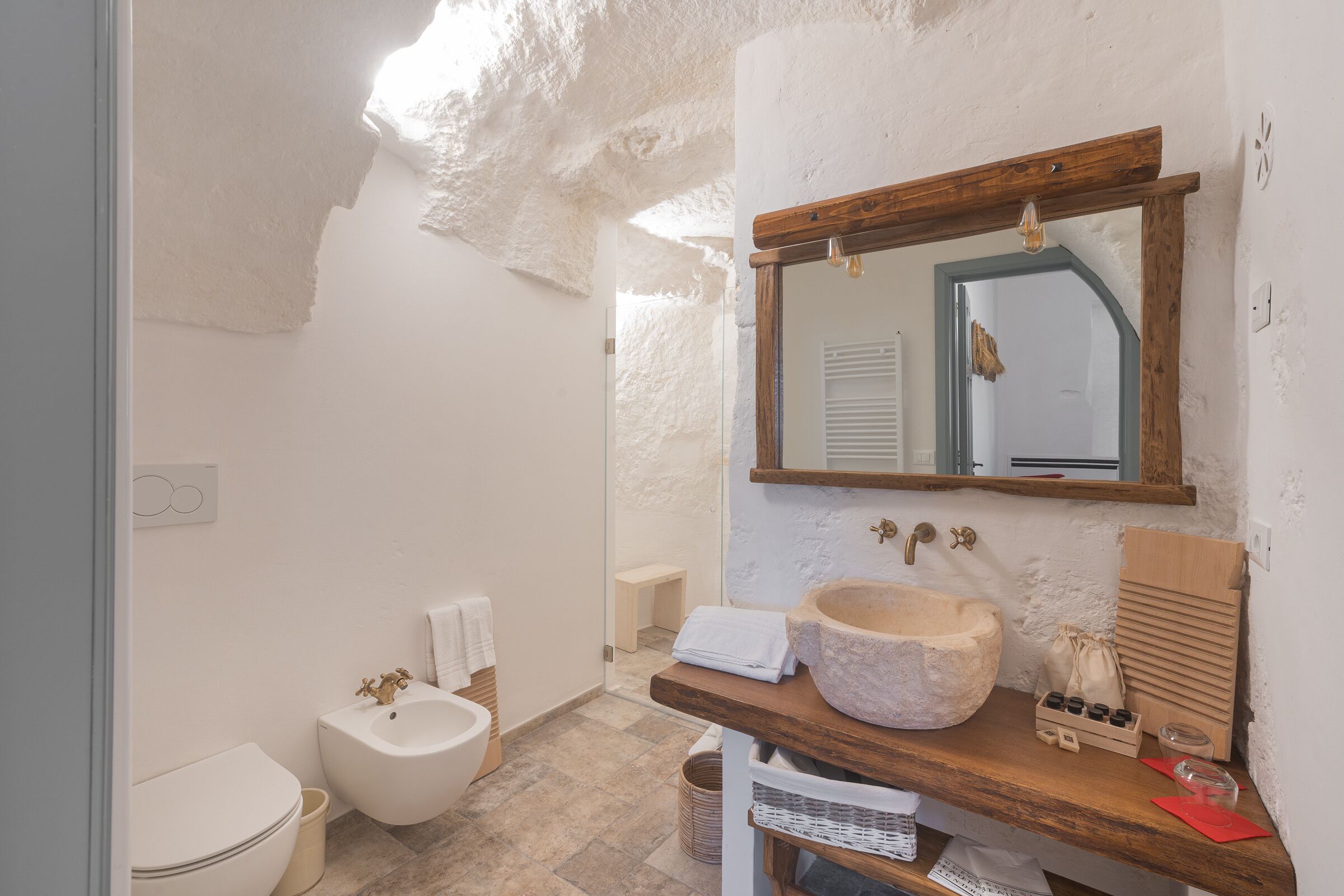 Une salle de bain avec un lavabo en pierre, un meuble-lavabo en bois et un miroir avec un cadre en bois.