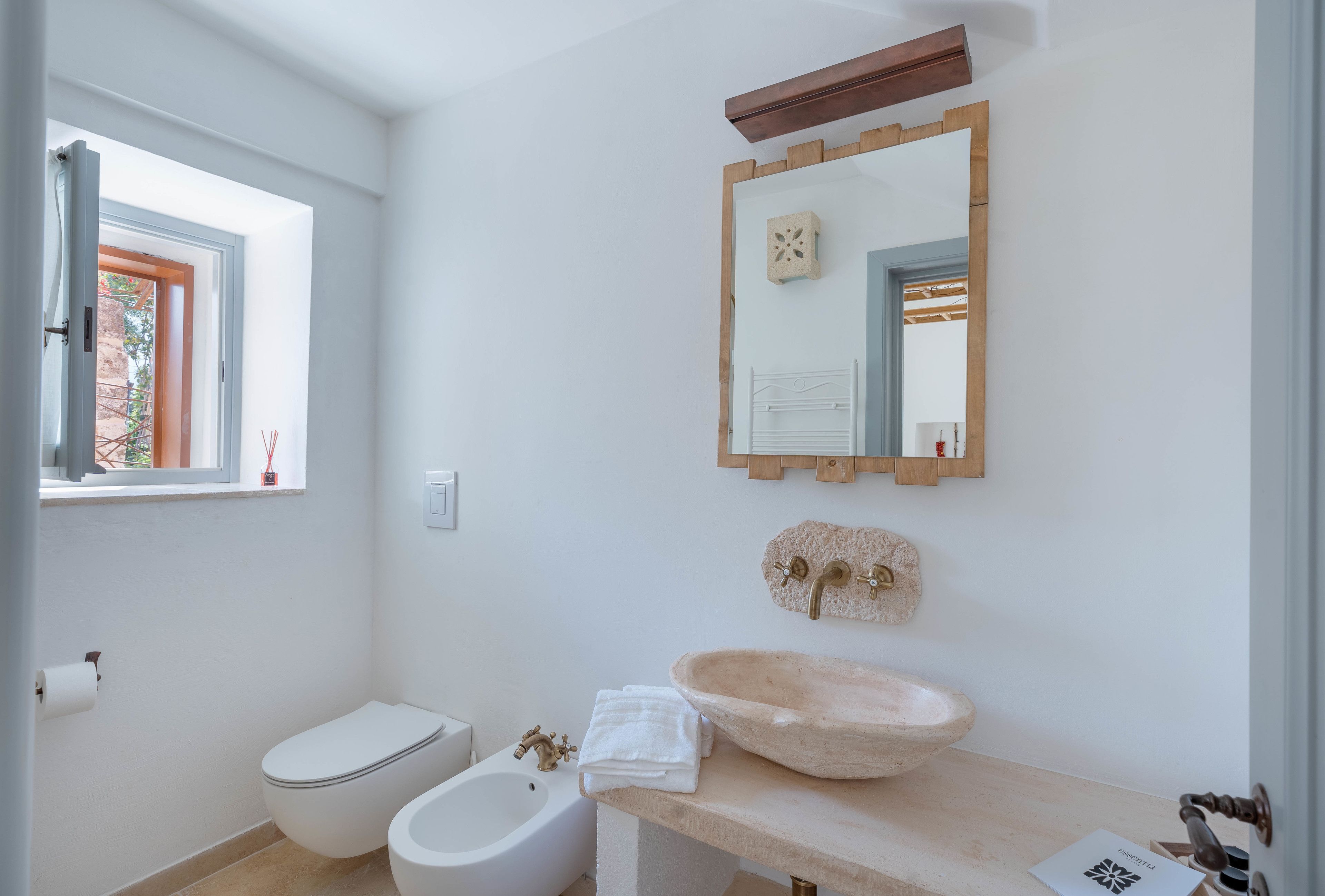 A modern bathroom with a toilet, bidet, and a large stone sink.