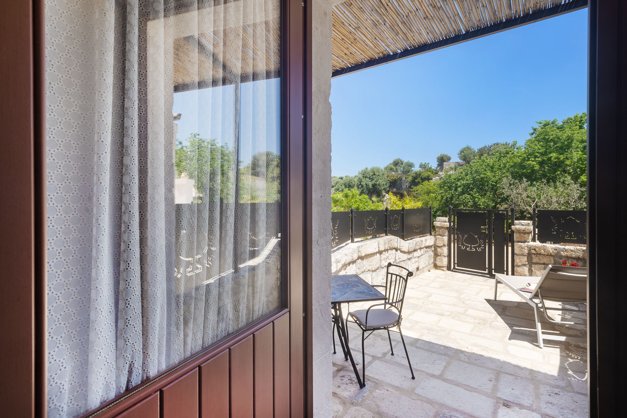Un patio con tavolo e sedie, un muro in pietra e vista su del verde.