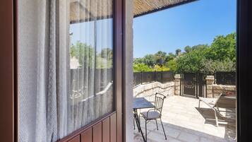 Un patio con tavolo e sedie, un muro in pietra e vista su del verde.