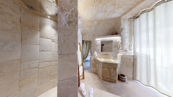A bathroom with a rustic design, featuring exposed brick walls, a wooden vanity, and a large mirror. - Masseria Torre Rossa (Fasano)