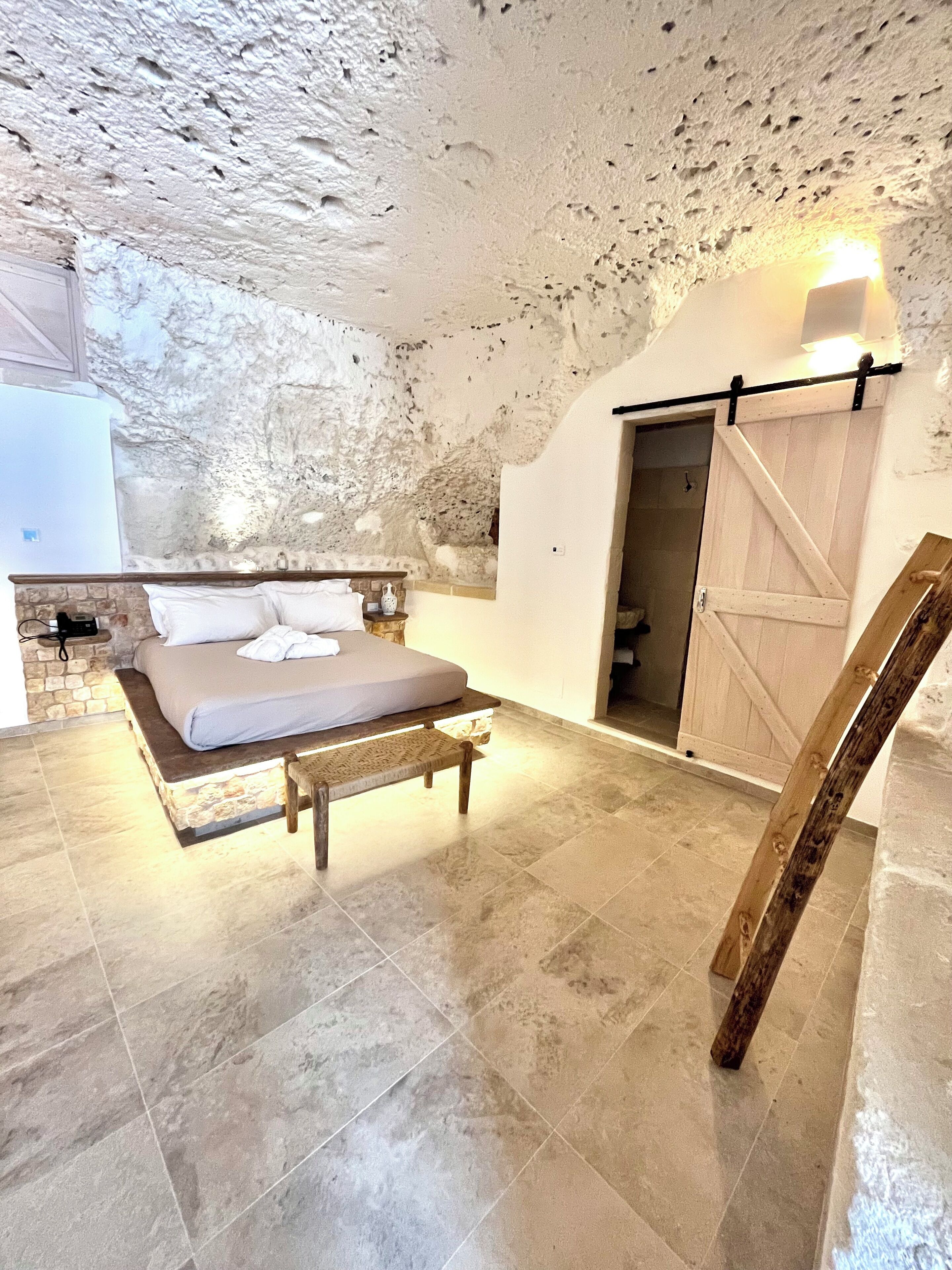 A bedroom with a bed, bench, and a wooden ladder.
