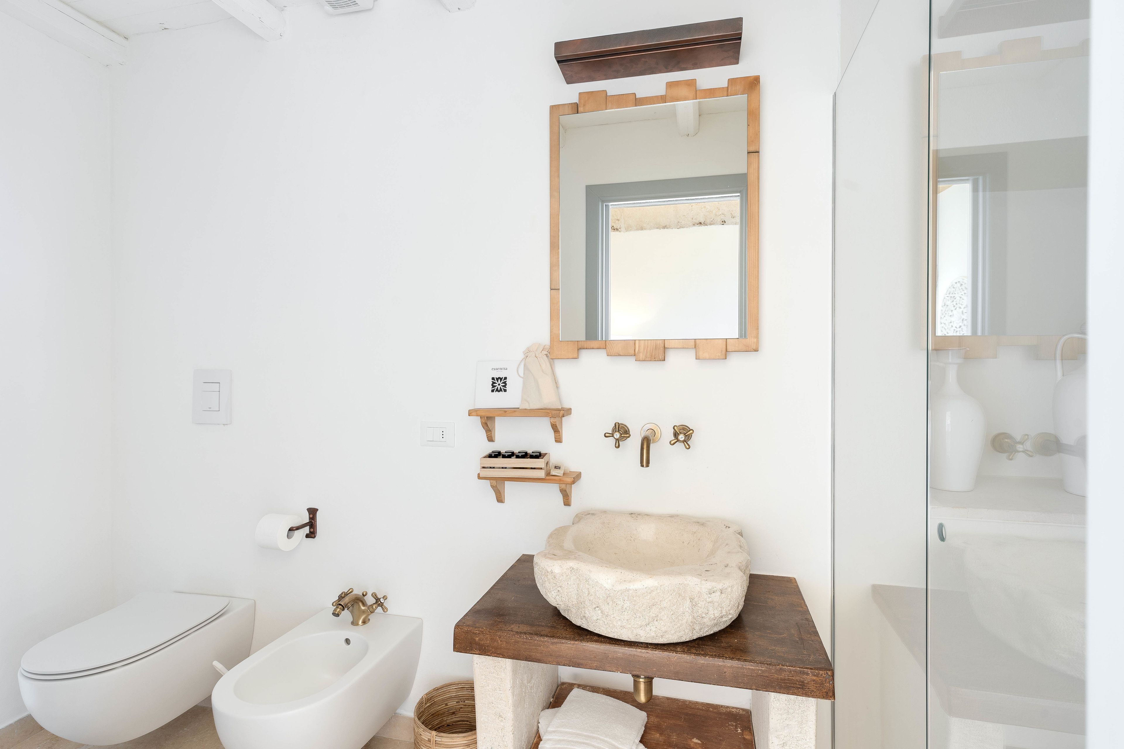 Un baño moderno con un lavamanos de piedra, un bidé y un espejo.