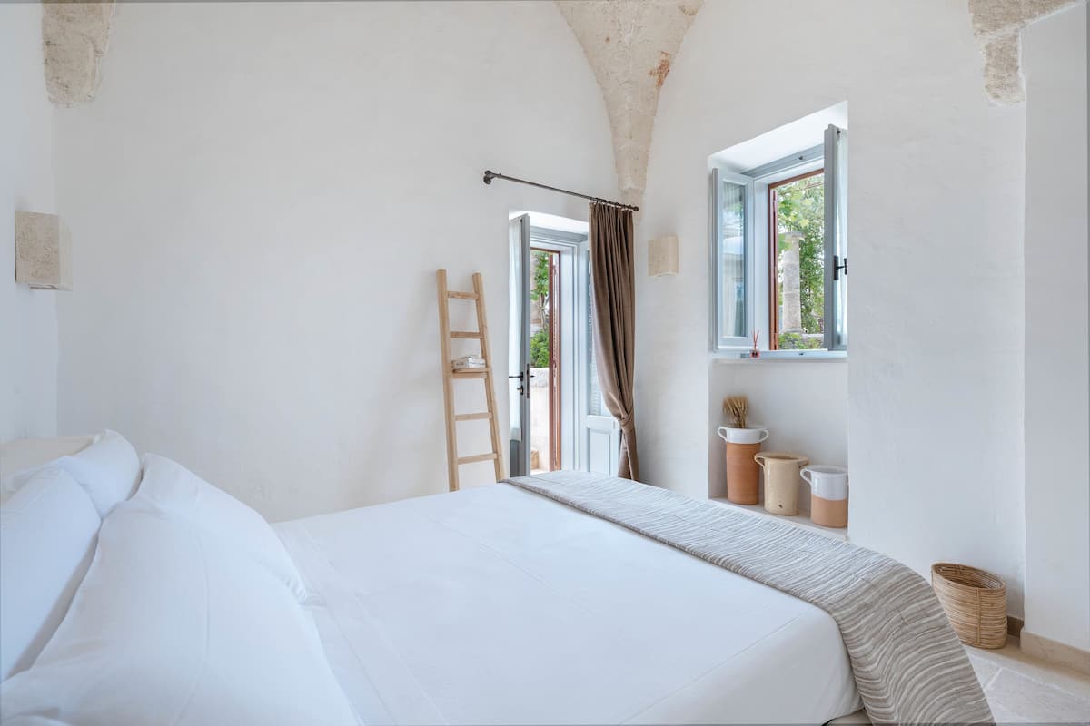 A bedroom with a bed, a window, a ladder, and a door.