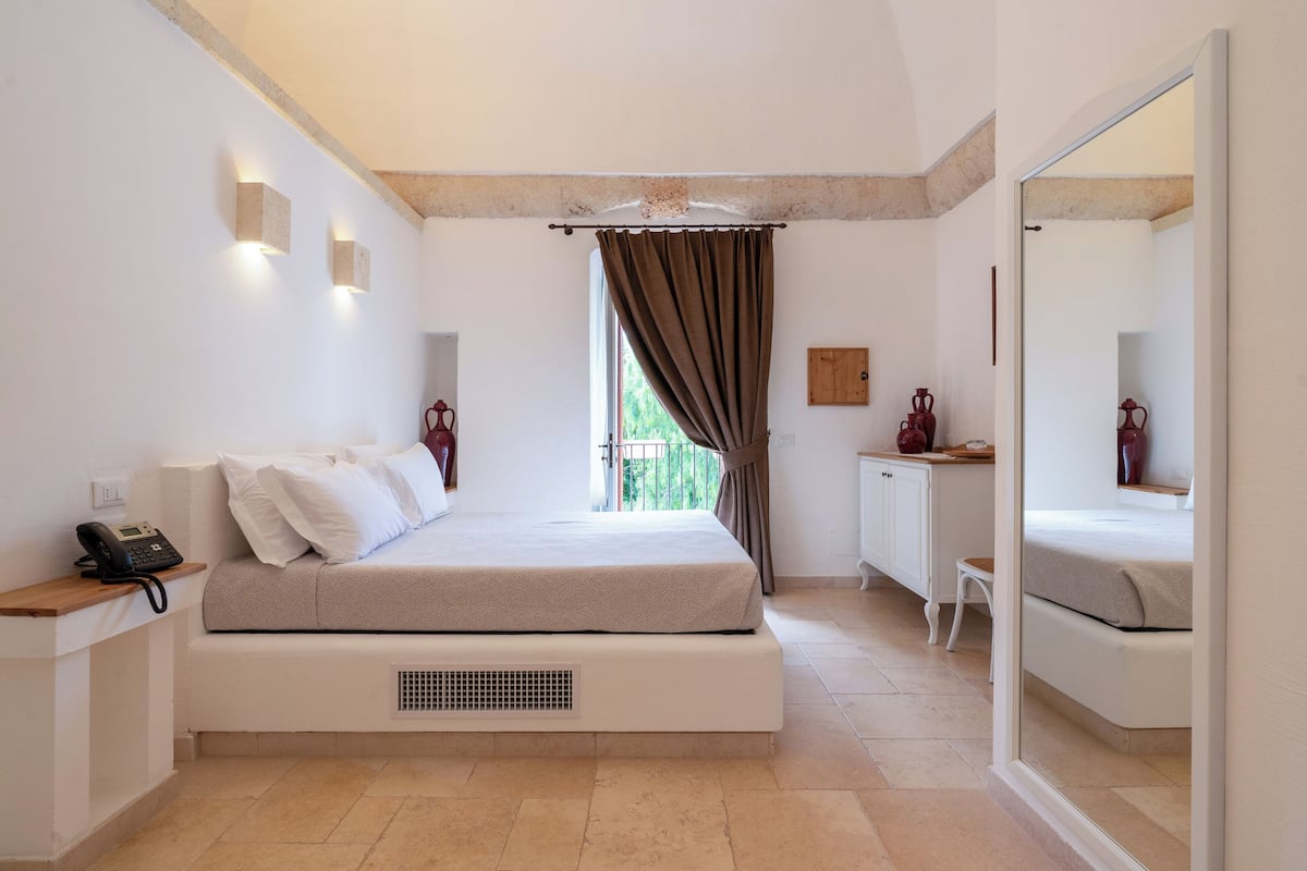 A bedroom with a bed, bedside table, and a small desk with a chair.