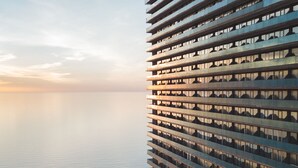 En høj bygning med moderne arkitektur, med en spejlvendt glasfacade og flere balkoner.