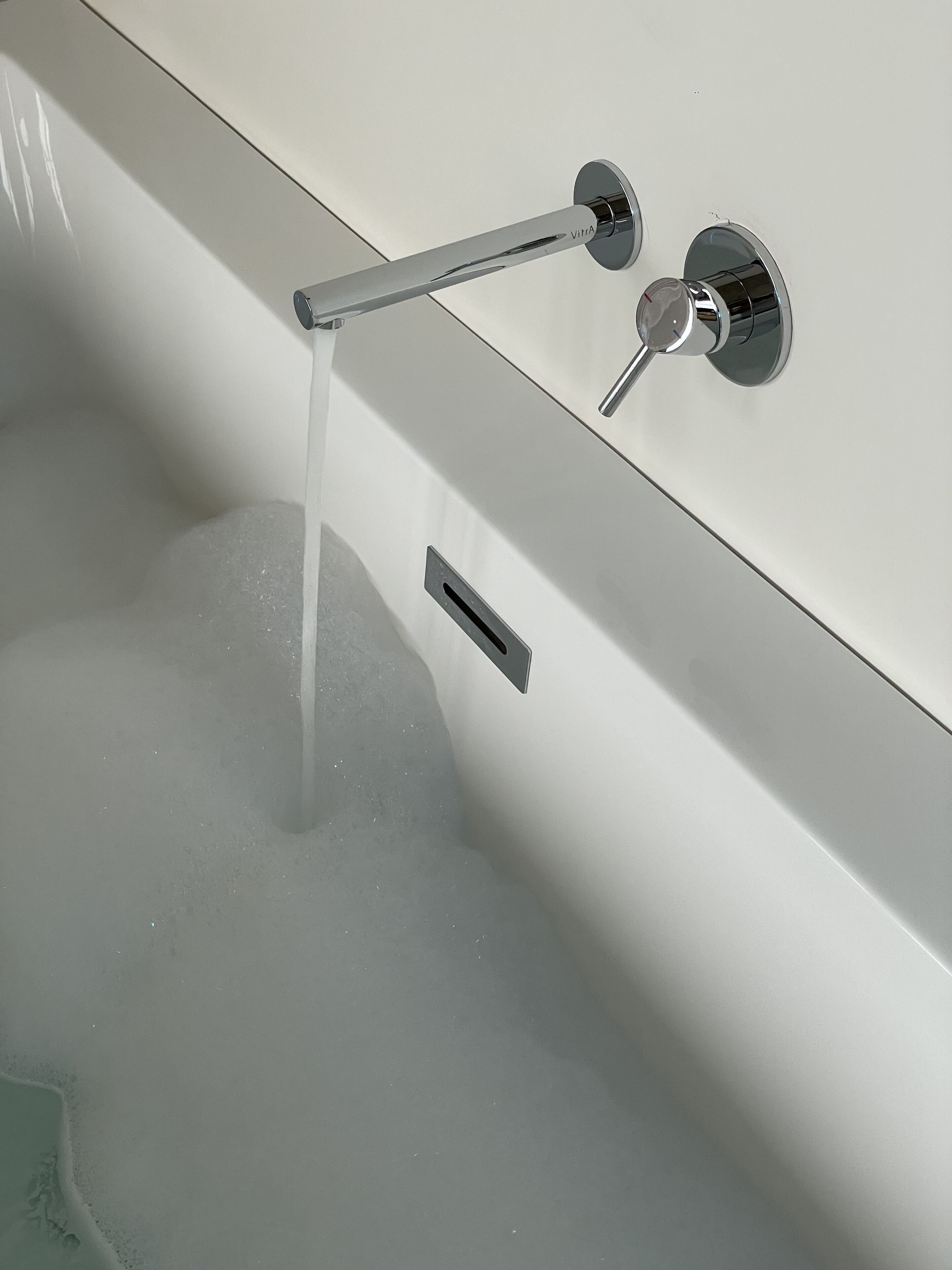 Una bañera con grifo cromado y ducha de mano.