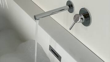 Una bañera con grifo cromado y ducha de mano.