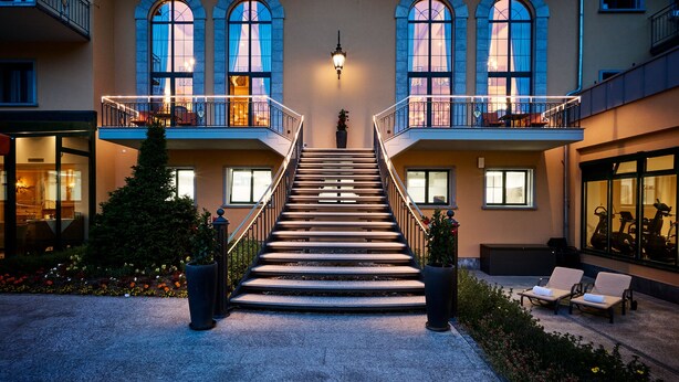 Ein Gebäude mit einer zentralen Treppe, mehreren Balkonen und großen Bogenfenstern.