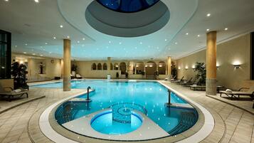 Een binnenzwembad, ligstoelen bij het zwembad