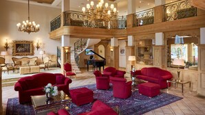 Eine geräumige Lobby mit einem Flügel, roten Sofas und einer Chandelier.