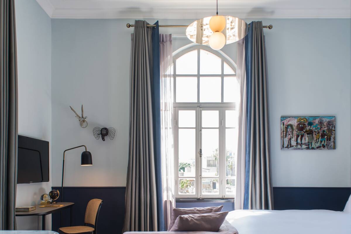 Une chambre à coucher avec un lit, un bureau, une chaise, un tapis et un tableau accroché au mur.