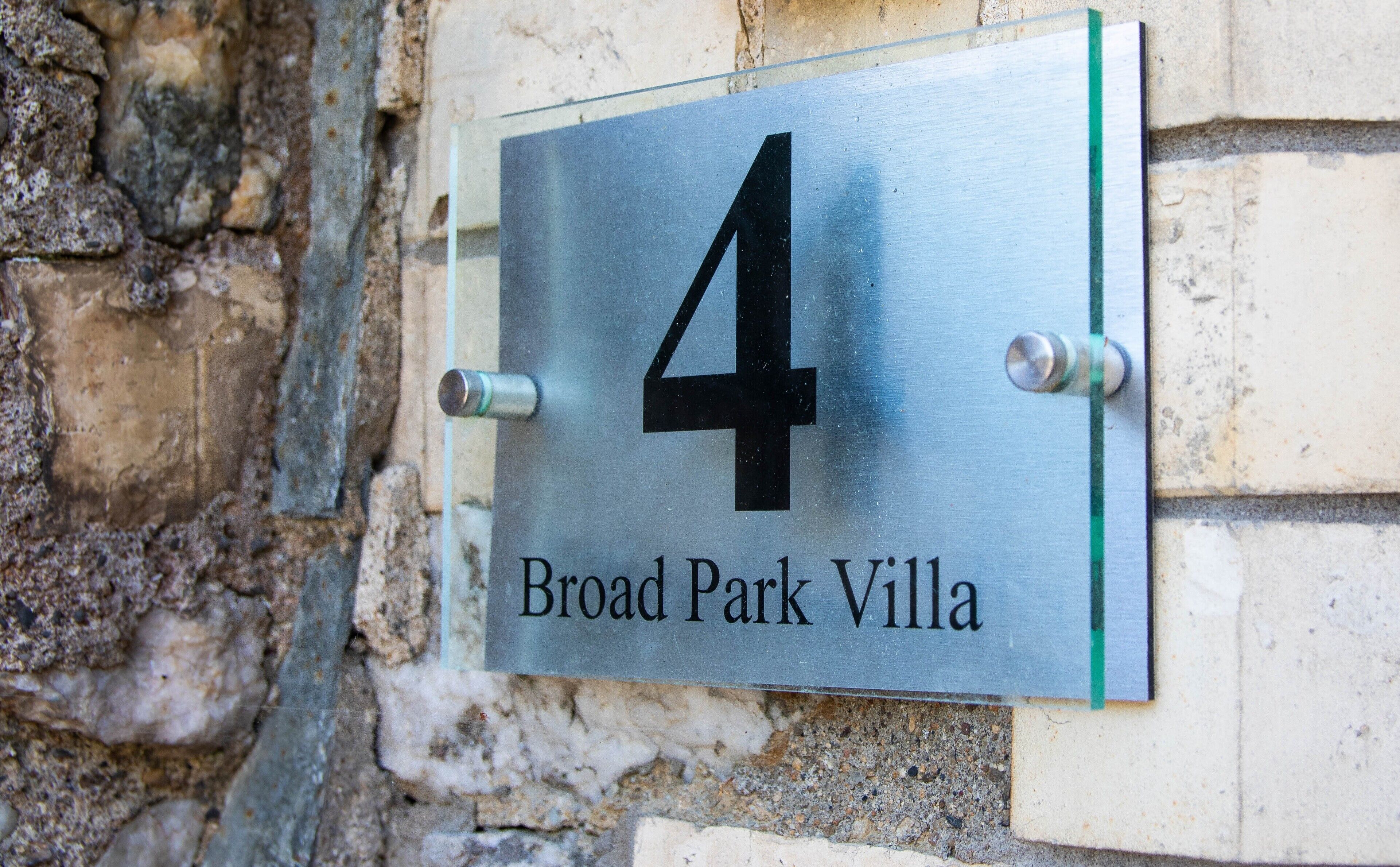 Een metalen bord met het cijfer 4 en de tekst 'Broad Park Villa', wat het adres van het gebouw aangeeft.