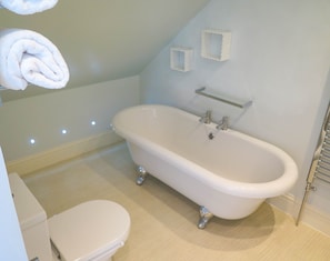 A bathroom with a white bathtub, a toilet, and a towel rack. - Broadpark Villa (Ilfracombe)