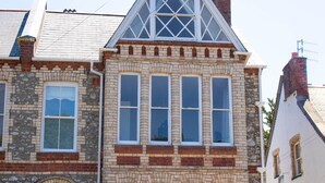 Ein zweistöckiges Steinhaus mit steiler Satteldachform, großen Fenstern und einem markanten Eingang mit Stufen.