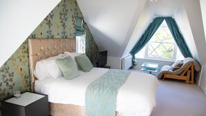 Ein Schlafzimmer mit einem großen Bett, einem Nachttisch, einem Fernseher und einem Fenster mit Vorhängen.