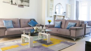 Ein Wohnzimmer mit zwei Sofas, einem Glastisch und einem Teppich mit Muster.