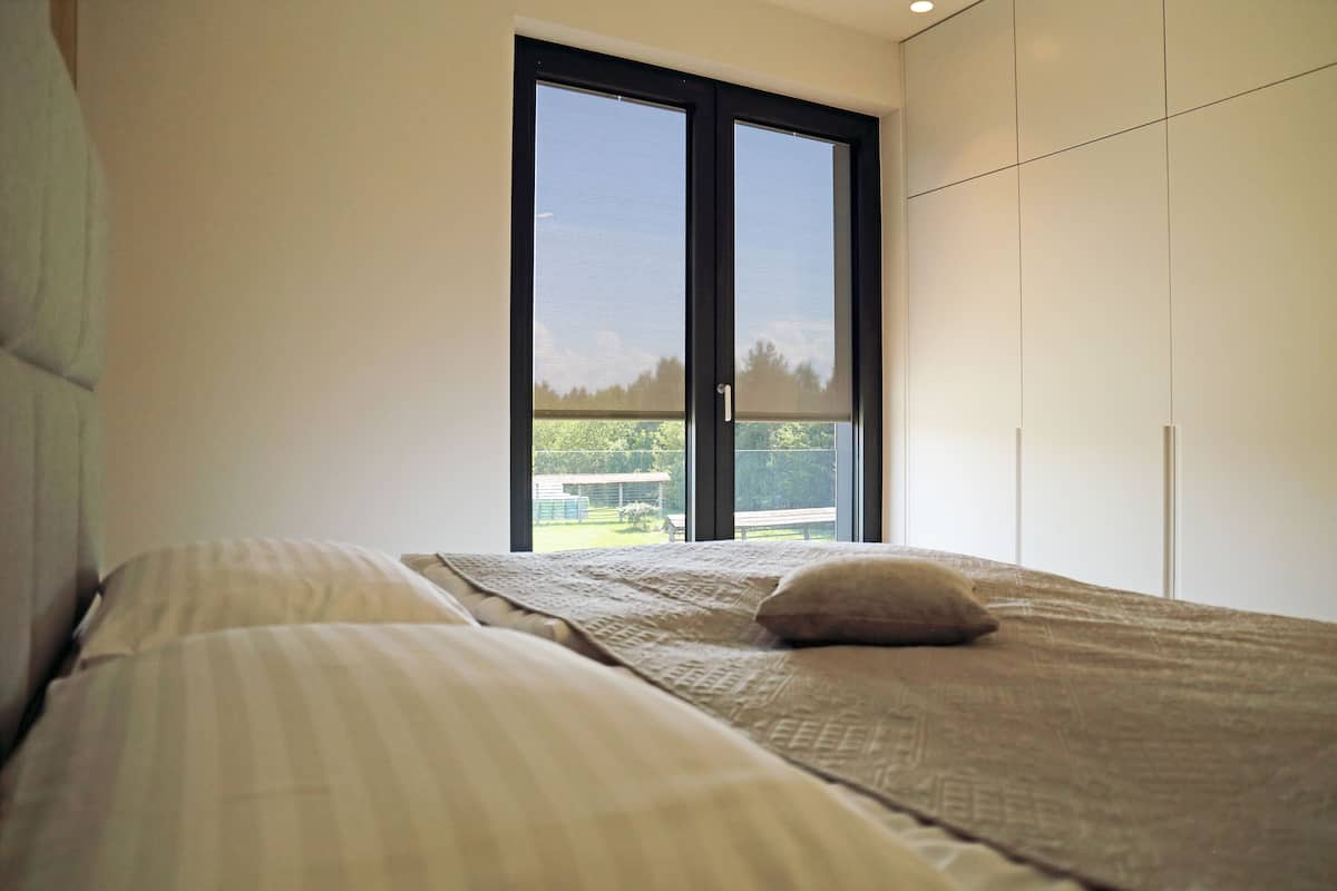 Un dormitorio con cama, ventana y vistas al exterior.