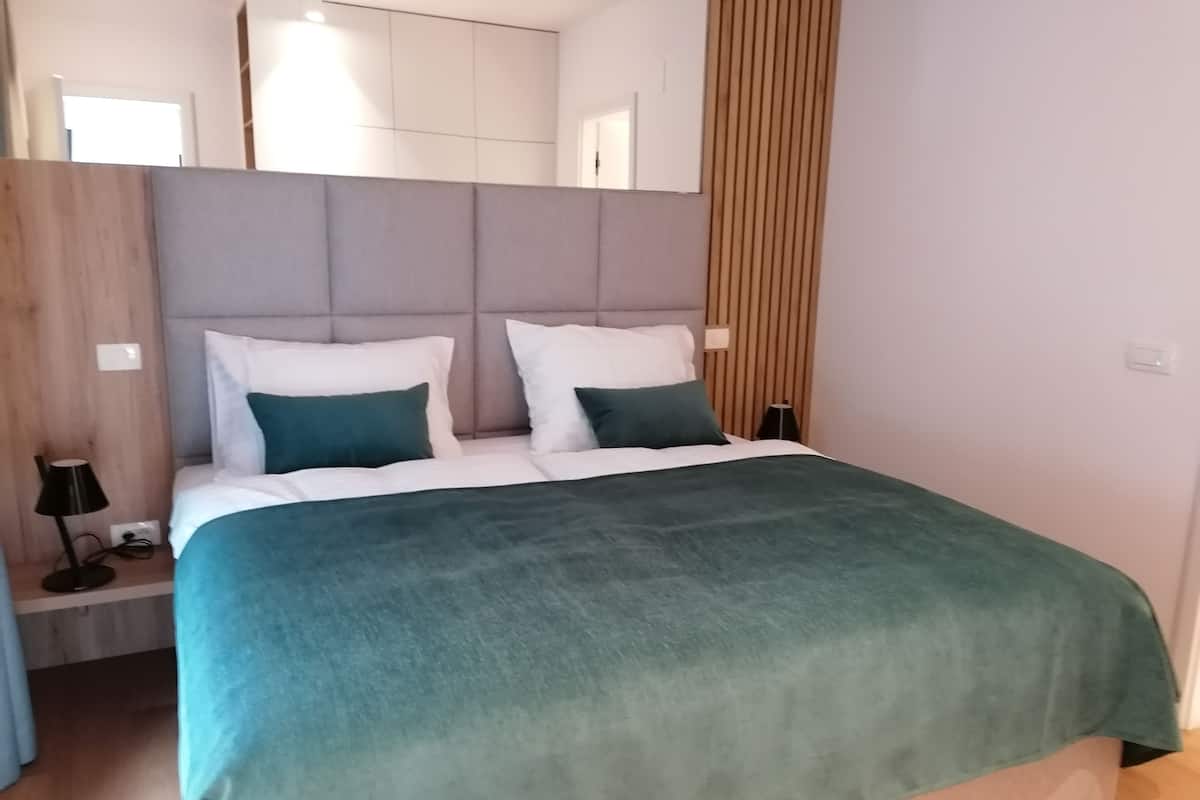 Un dormitorio moderno con una cama grande, cabecera, mesitas de noche y un espejo.